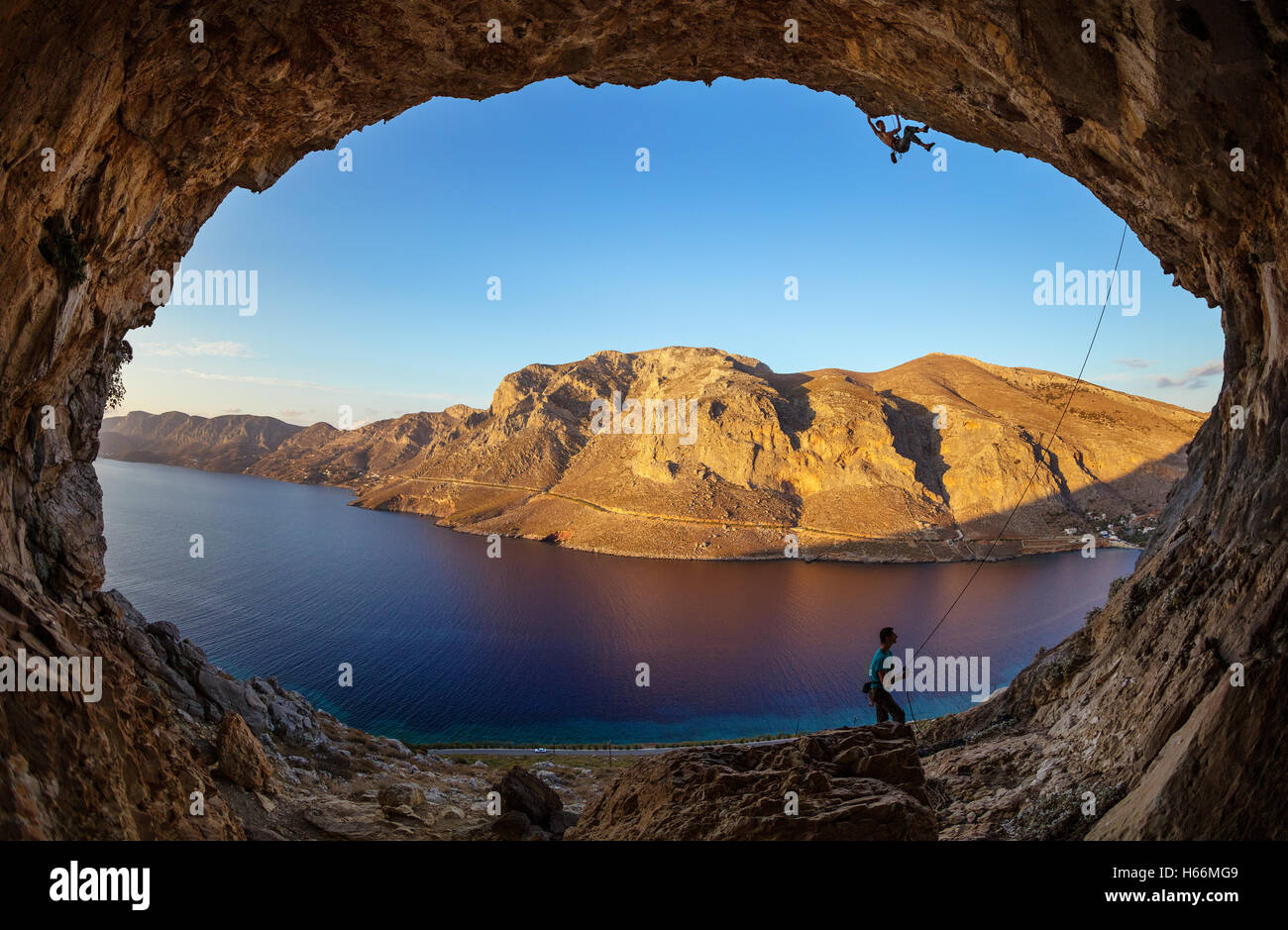 Maschio di rocciatore sul percorso impegnativo nella grotta, il suo partner belaying Foto Stock