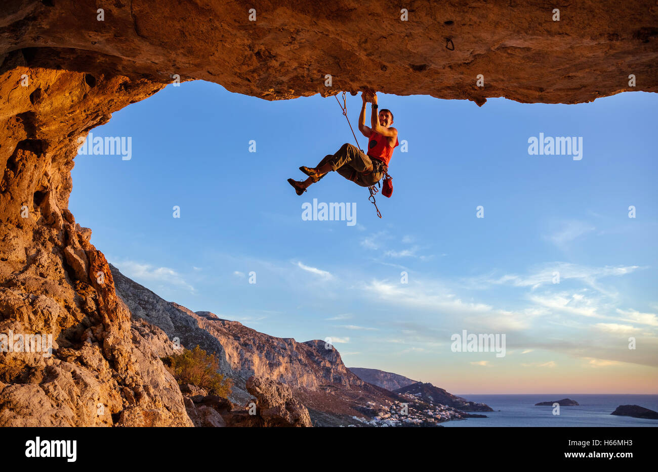 Scalatore maschio sul percorso impegnativo in grotta contro la bella vista costiera Foto Stock