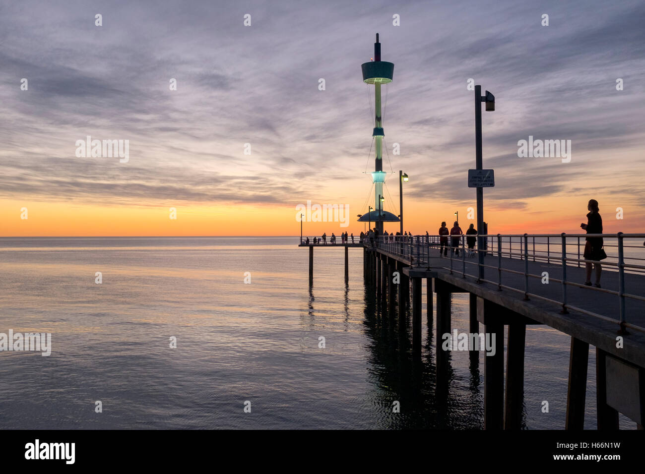 Le persone si godono una passeggiata al tramonto lungo il molo presso la spiaggia Brighton di Adelaide, Adelaide Australia Foto Stock