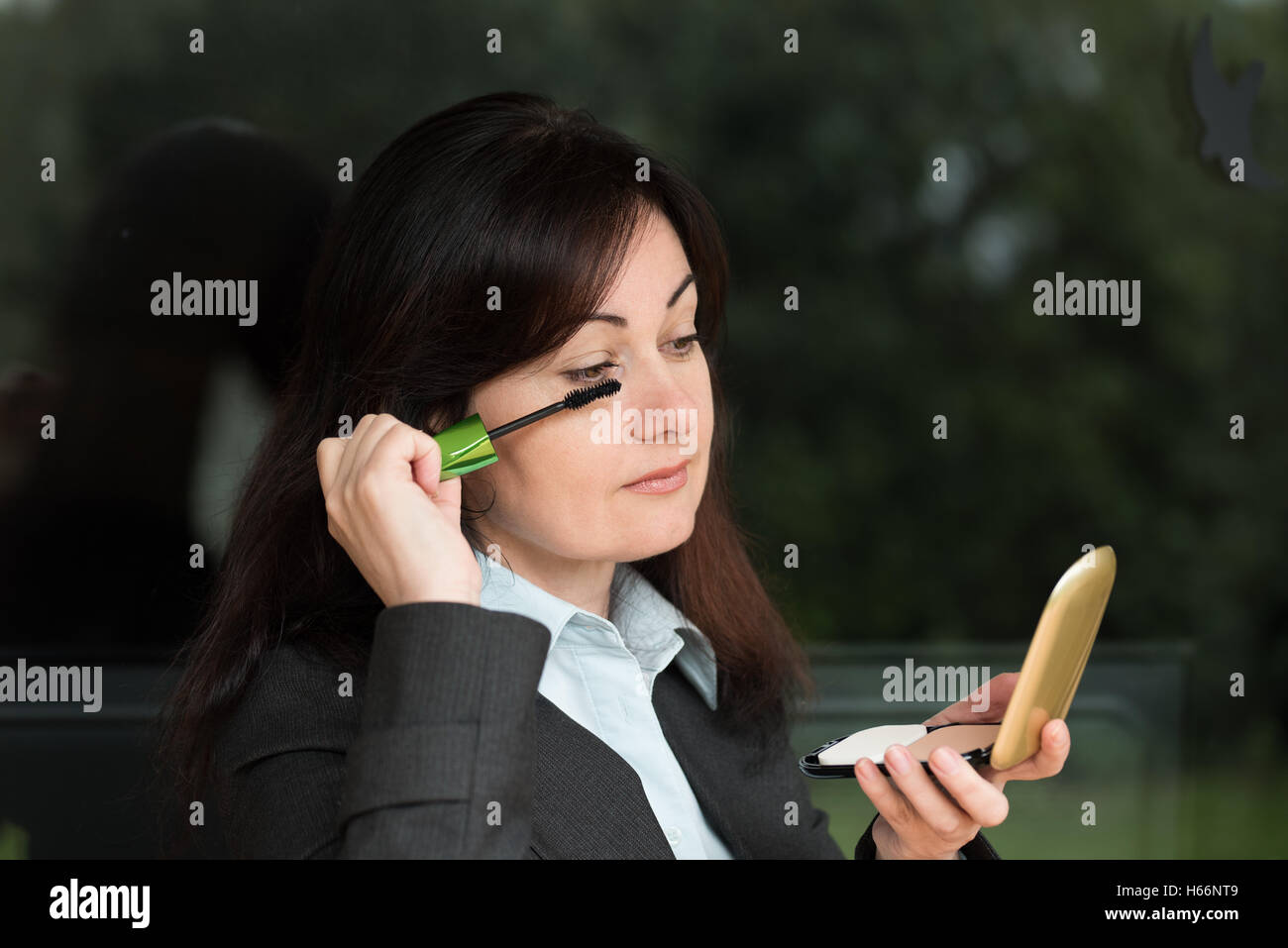 Donna di mezza età in business suit mette il make-up su i suoi occhi Foto Stock Donna di mezza età in business suit mette il make-up su i suoi occhi Foto Stock
