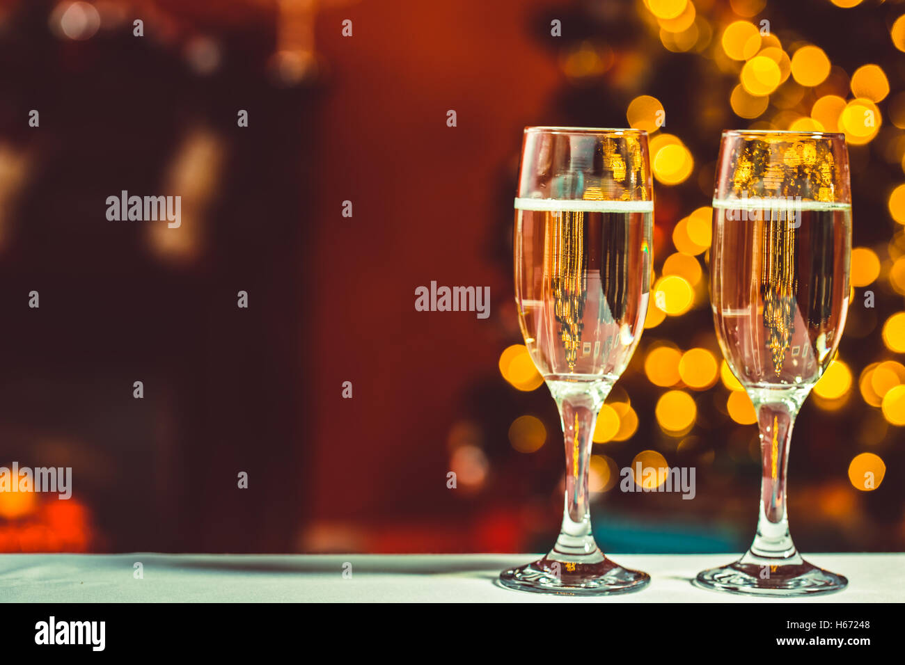 Bella due bicchieri di champagne in piedi sulla tavola sullo sfondo di una stanza sfocata con un albero di Natale decorato e Foto Stock