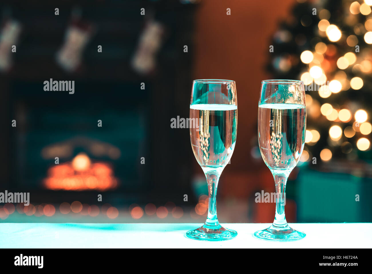 Bella due bicchieri di champagne in piedi sulla tavola sullo sfondo di una stanza sfocata con un albero di Natale decorato e Foto Stock