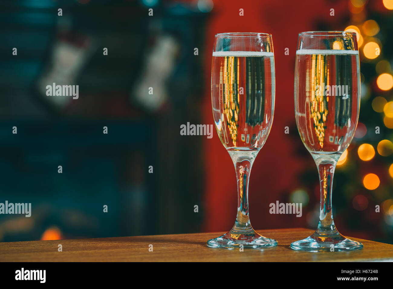 Bella due bicchieri di champagne in piedi sulla tavola sullo sfondo di una stanza sfocata con un albero di Natale decorato e Foto Stock
