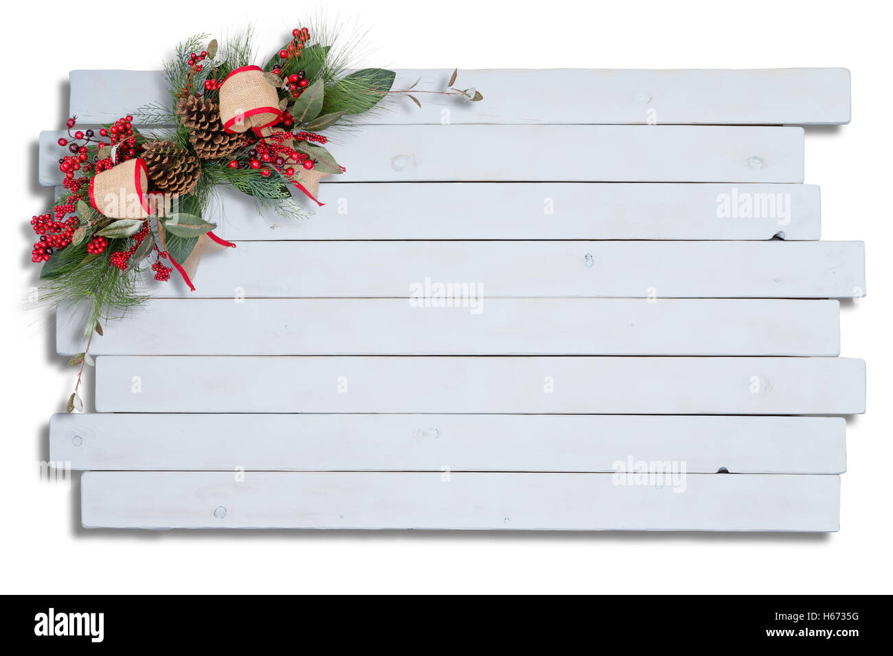 Rustico elegante decorazione di Natale con fogliame verde, pigne, bacche rosse e il nastro disposti nell'angolo in legno bianco Foto Stock