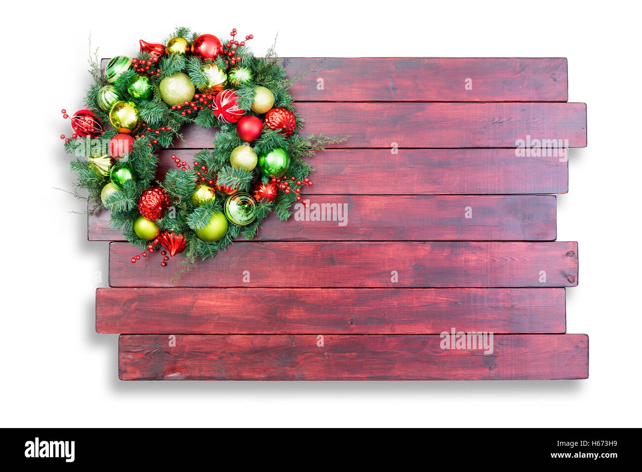 I tradizionali colorati ghirlanda di Natale appeso nell'angolo in mogano sfalsati macchiato di tavole di legno con copia spazio su un whi Foto Stock