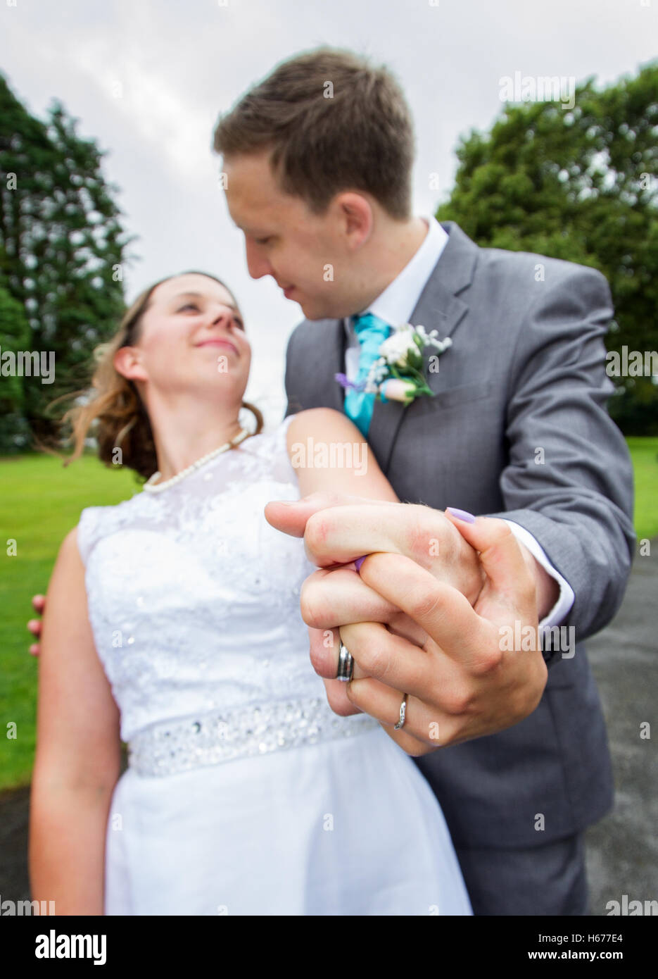Sposa e lo sposo tenendo le mani cercando in ogni altri occhi, prese con obiettivo fisheye per aggiungere dramma Foto Stock