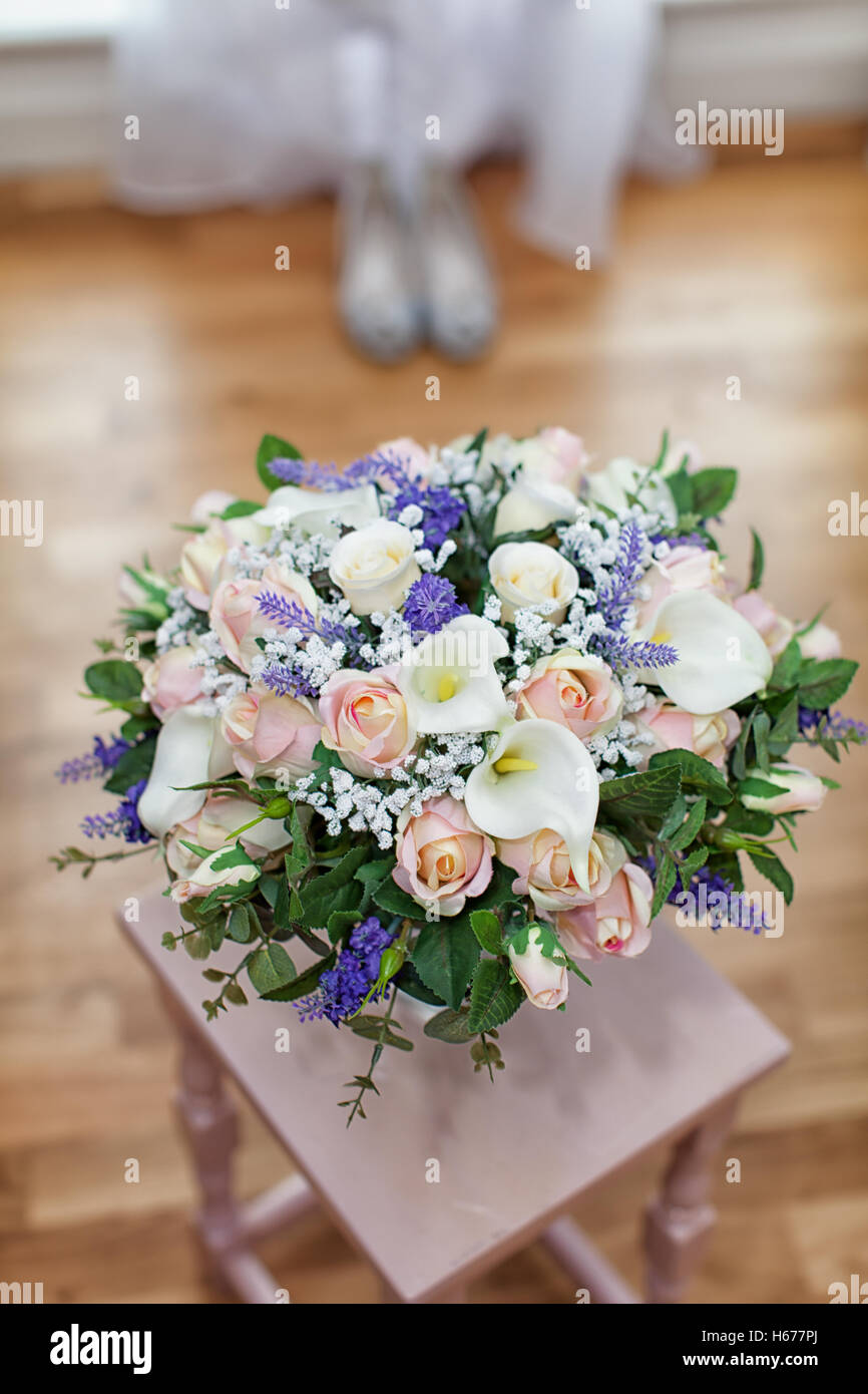 Bridal bouquet di fiori pronto per un giorno di nozze. Preso in formato verticale con le scarpe di nozze in background Foto Stock