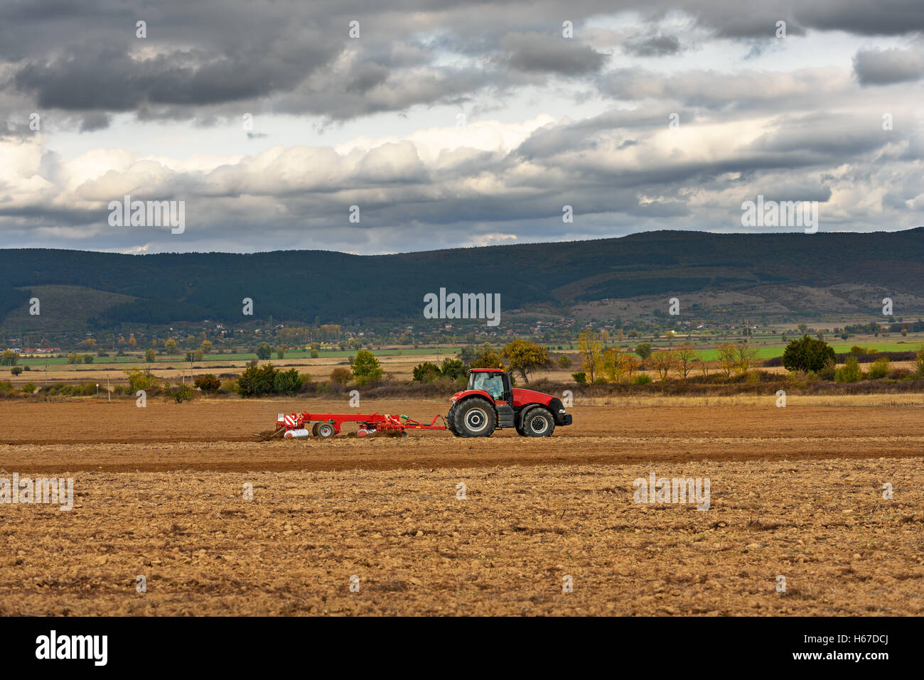 Il trattore arare un campo al crepuscolo Foto Stock