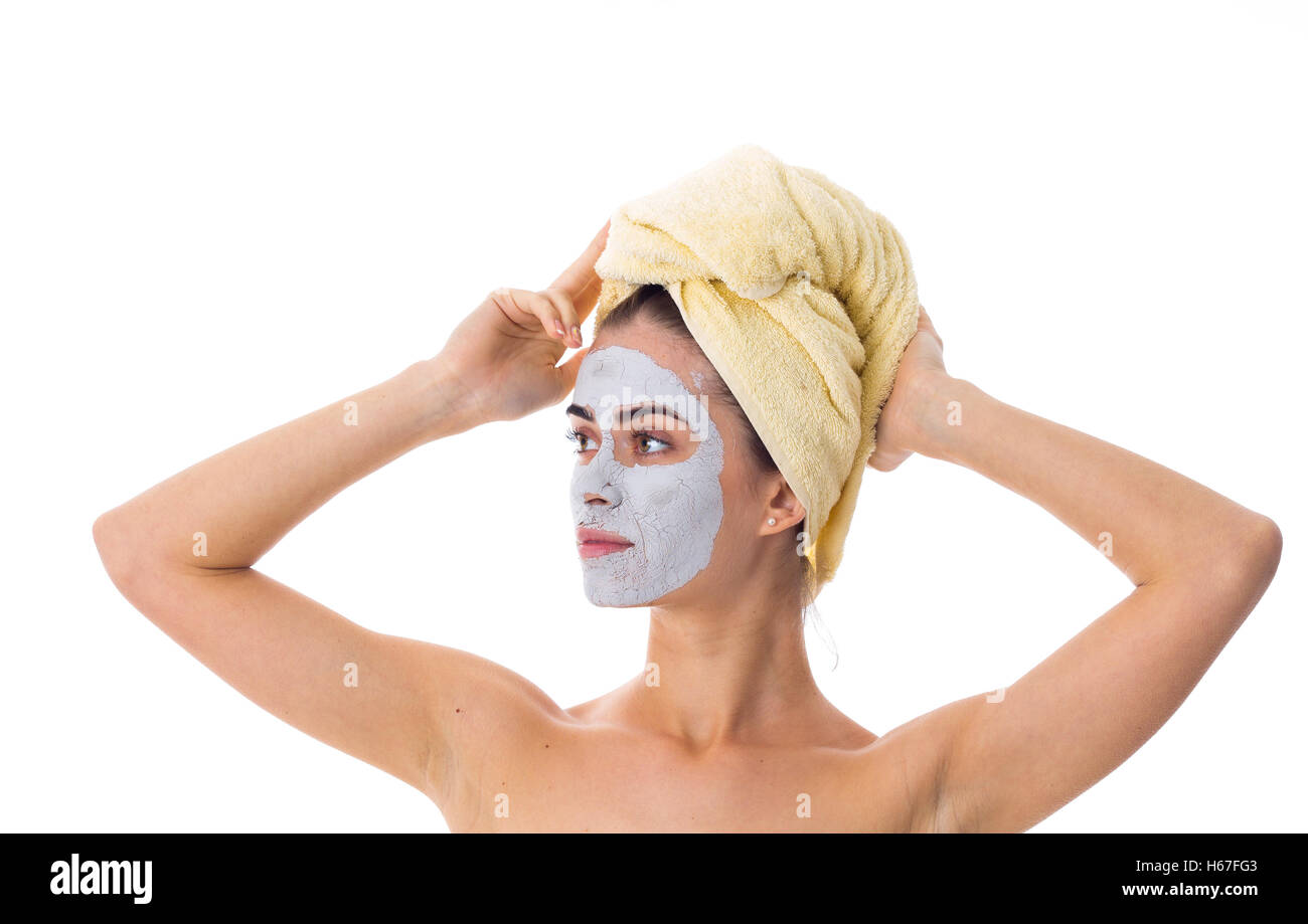 Donna con asciugamano sul suo capo e la maschera di cosmetici sul suo viso Foto Stock