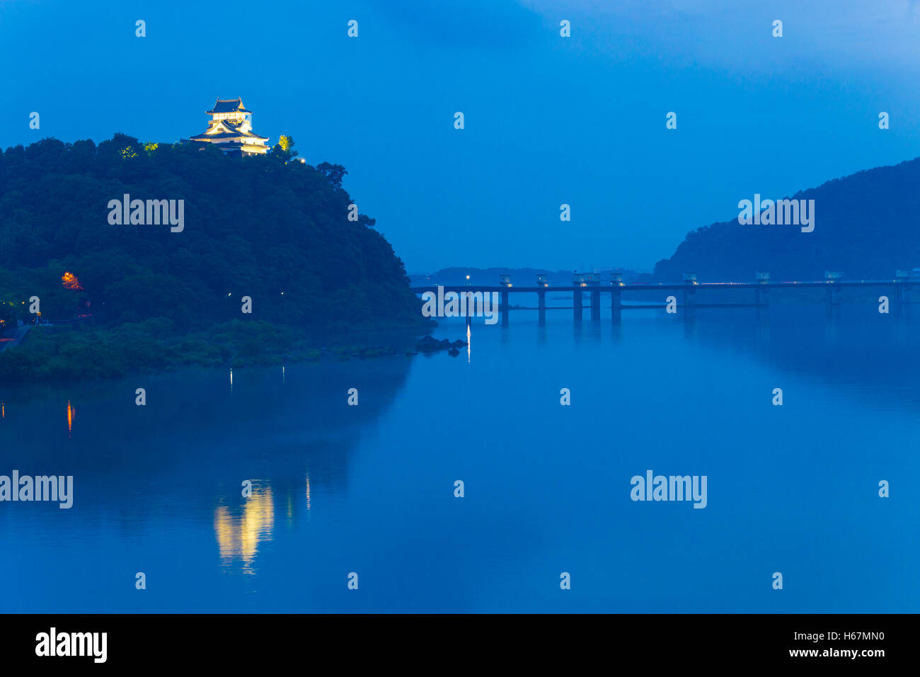 Vicino al buio a lontano Inuyama castello illuminato da faretti sopra il fiume Kiso al tramonto nella Prefettura di Gifu, Giappone Foto Stock