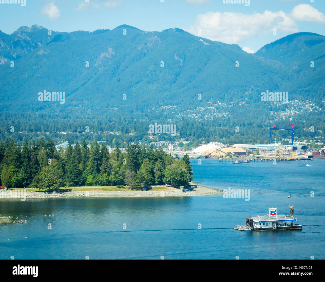 Vista in elevazione: Coal Harbour, floating Chevron la stazione di benzina, Stanley Park, il porto di Vancouver e Grouse Mountain. Vancouver. Foto Stock