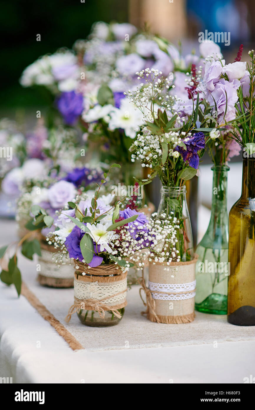 Nozze rustico decor, stile provenzale. Lavanda bouquet di fiori di campo e vetro vasetti di spezie sul tavolo di legno Foto Stock
