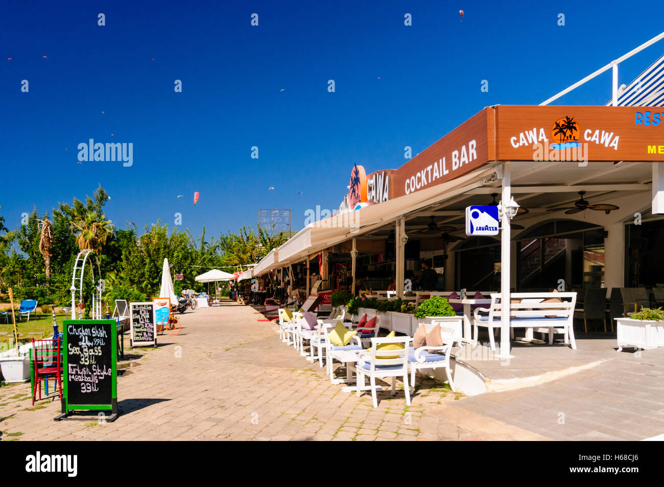 Decine di parapendio nel cielo sopra i negozi in Oludeniz, Turchia Foto Stock