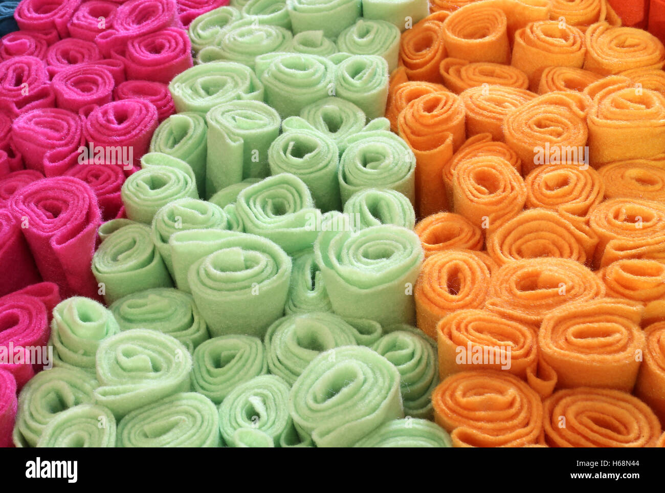 Molti rulli di feltro colorato per la vendita nel mercato in stallo di tessuti Foto Stock