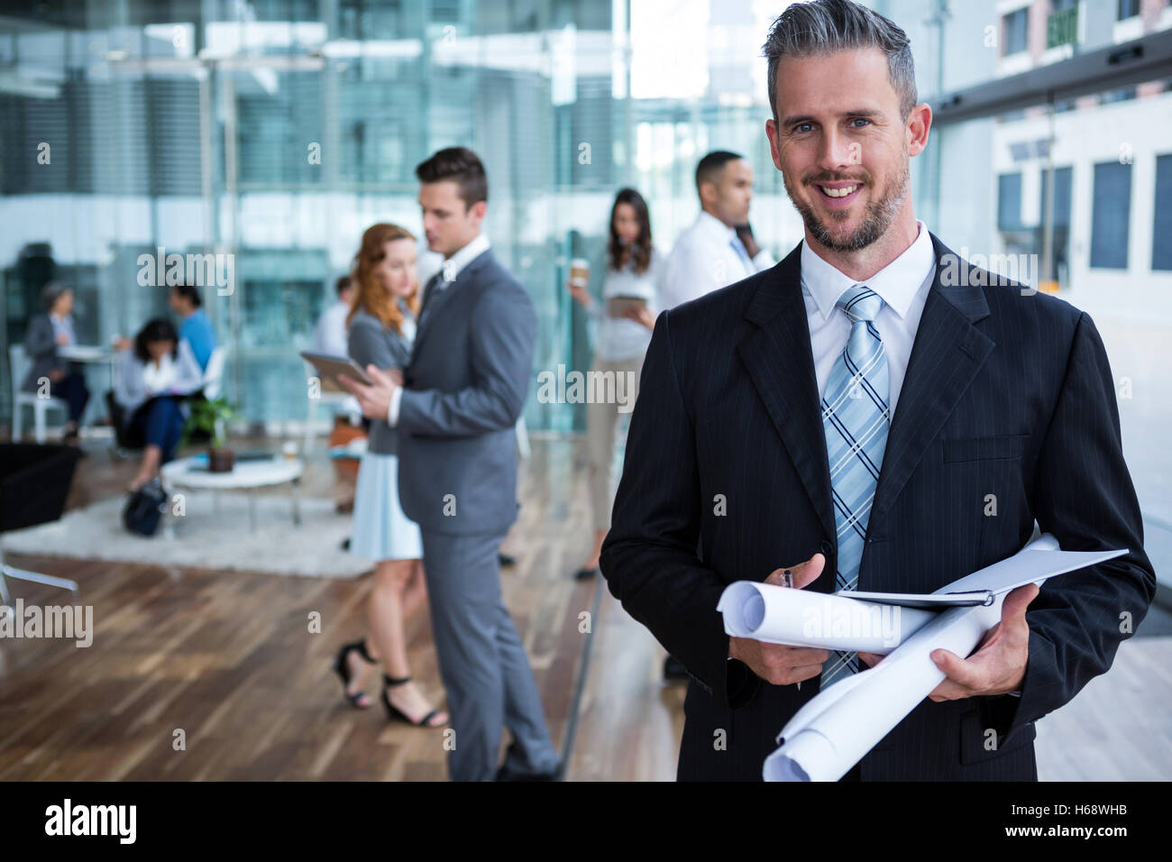 Imprenditore sorridente in piedi con documento di Office Foto Stock