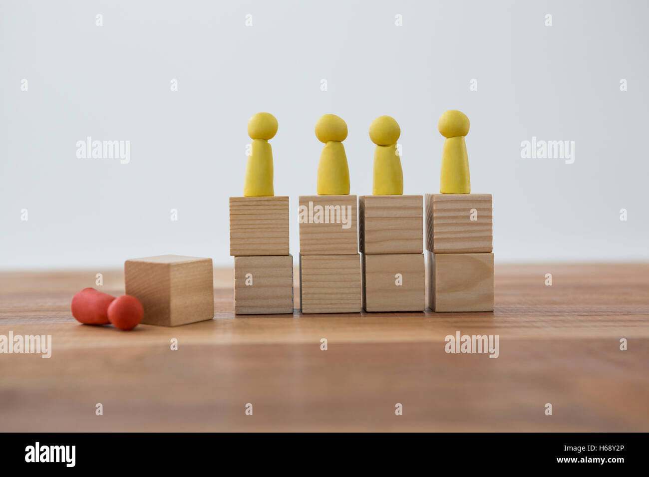 Figurine di giallo su blocchi di legno in una fila e figurine Rossa caduti a terra Foto Stock