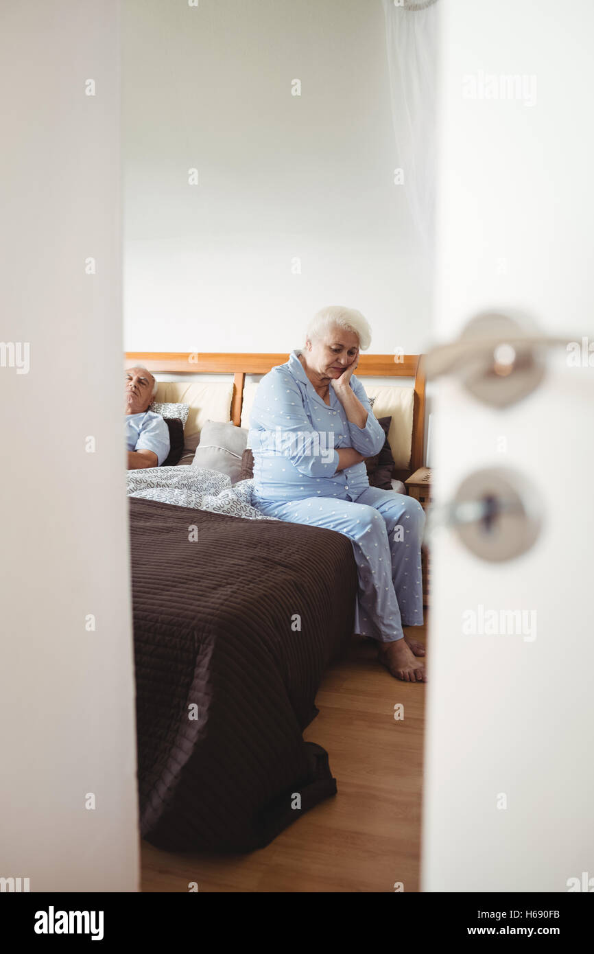 Preoccupato senior donna seduta sul letto Foto Stock