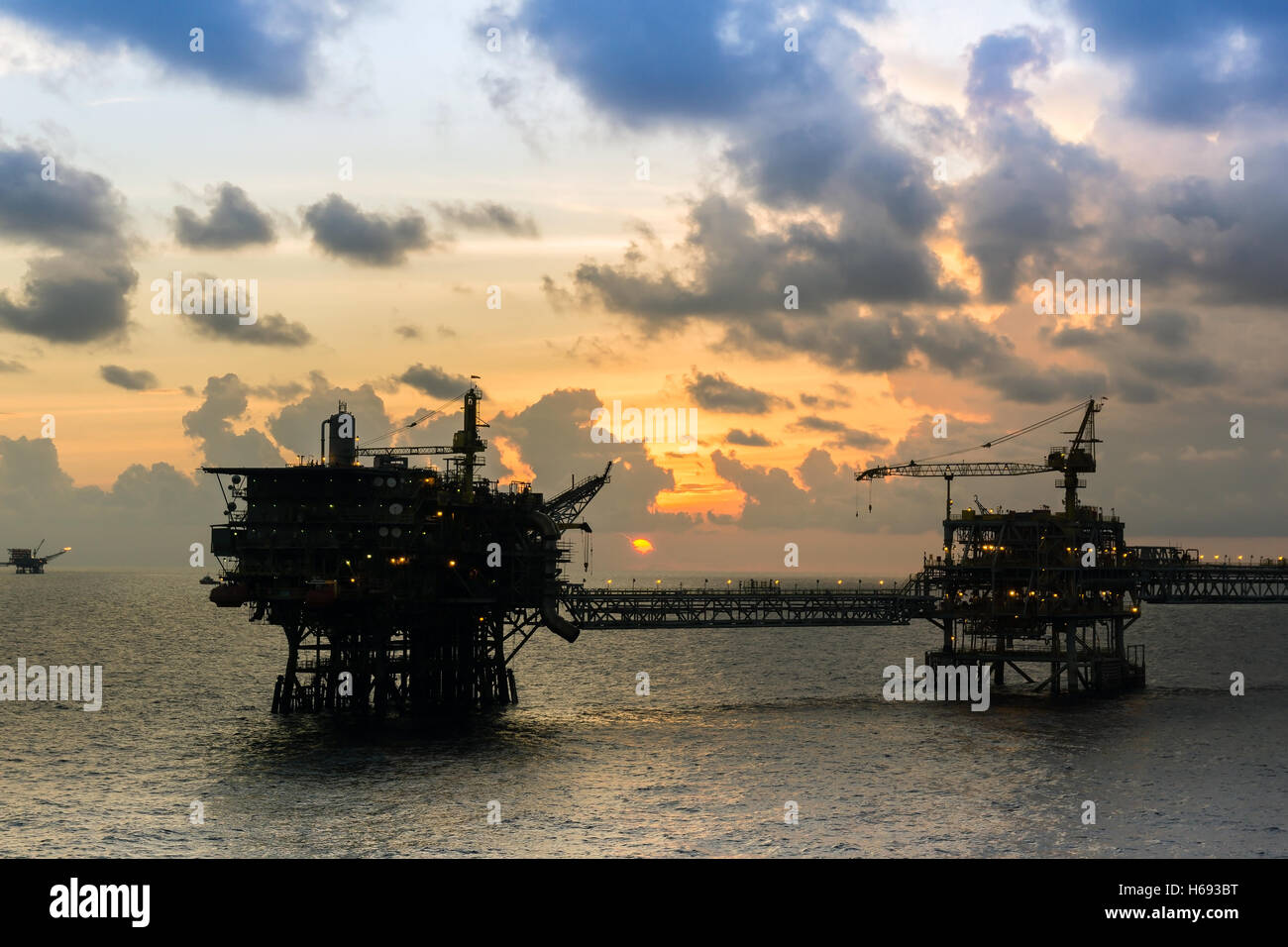 Silhouette di piattaforme petrolifere collegata con un ponte di sera a oilfield Foto Stock
