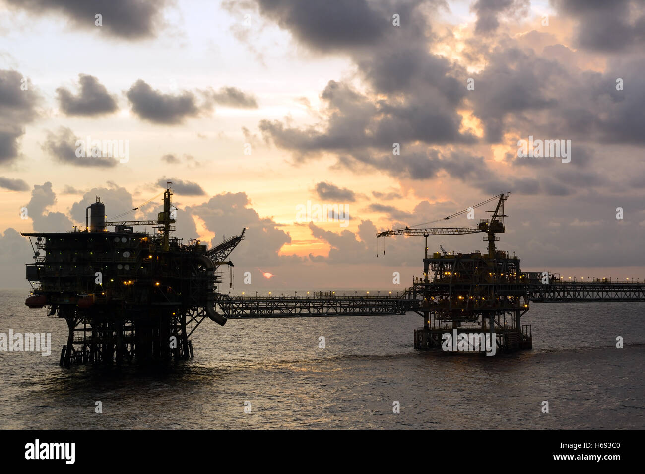 Silhouette di piattaforme petrolifere collegata con un ponte di sera a oilfield Foto Stock