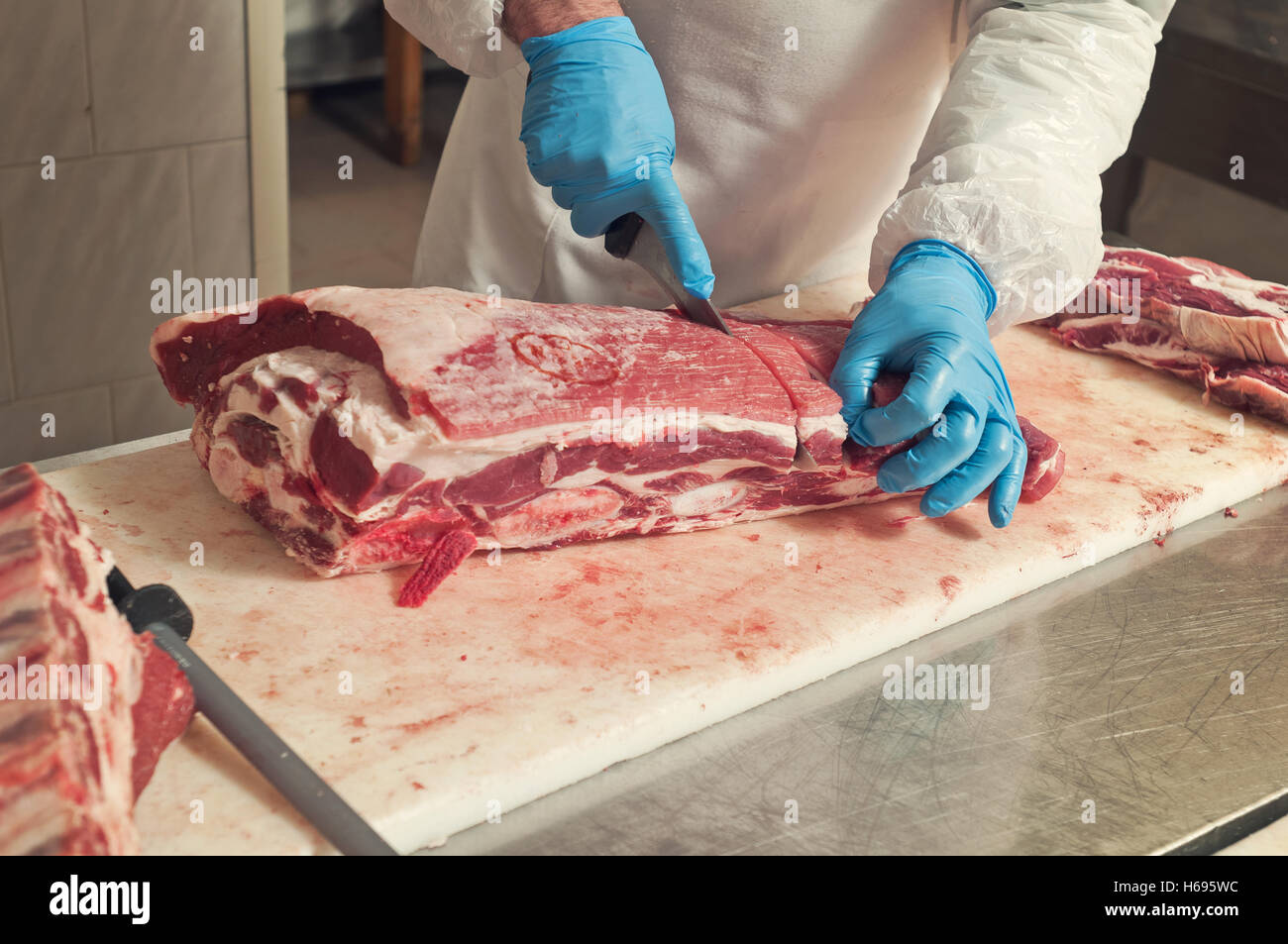 Primo piano della mano il macellaio taglia un grande pezzo di carne di manzo Foto Stock