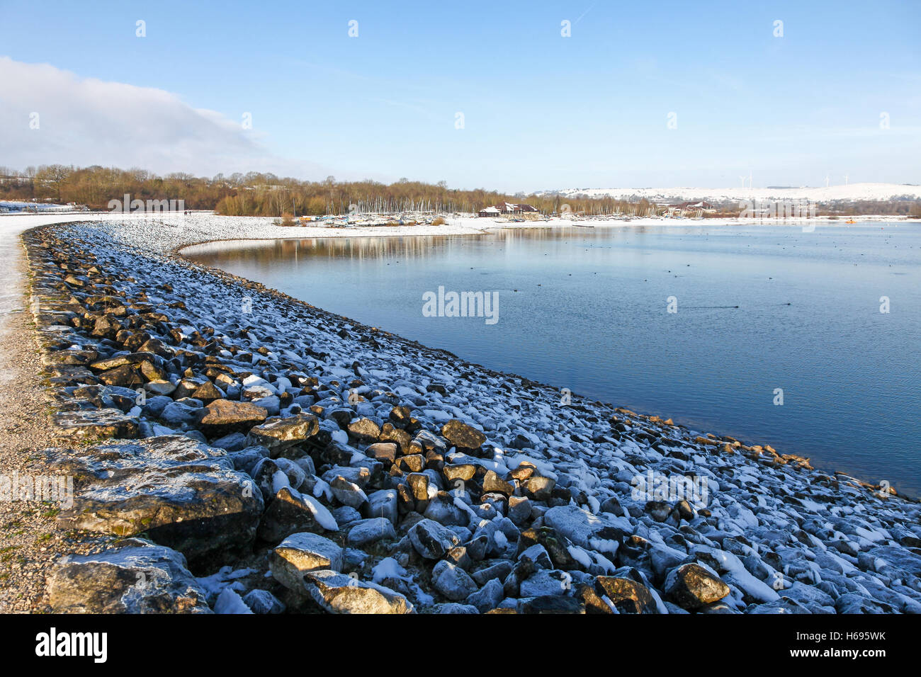 Rocce ghiacciate sulla diga a Carsington serbatoio acqua in inverno con neve sul terreno Derbyshire England Regno Unito Foto Stock