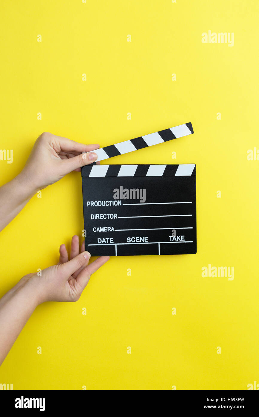 Donna che mantiene il filmato battaglio su sfondo giallo, concetto di cinema Foto Stock