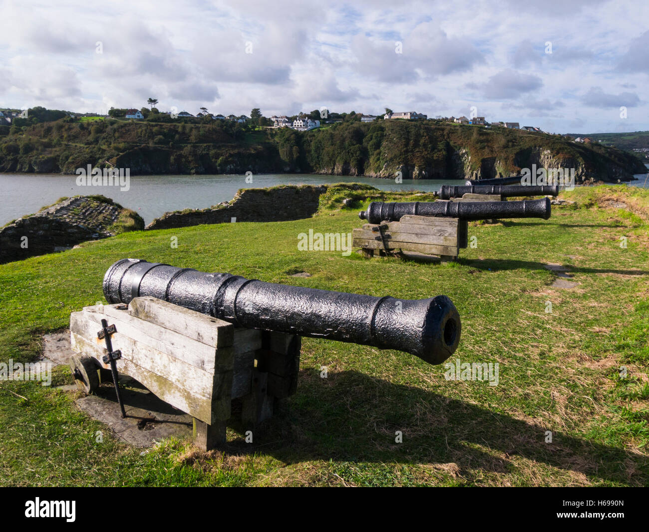 Quattro 9 pounder guns nelle rovine di Fishguard Fort costruito 1781 a guardia porto fiorente Pembrokeshire South Wales UK vista attraverso Fishguard Bay Foto Stock