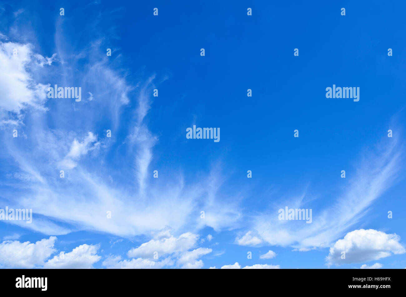 Cirrus nubi sparse con piccole cumulus nubi in un luminoso cielo blu Foto Stock