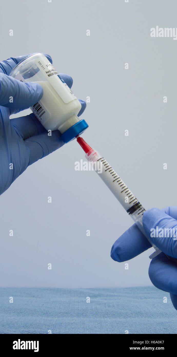 Due mani che revoca un agente anestetico propofol (Michael Jackson farmaco) da una fiala con una siringa Foto Stock