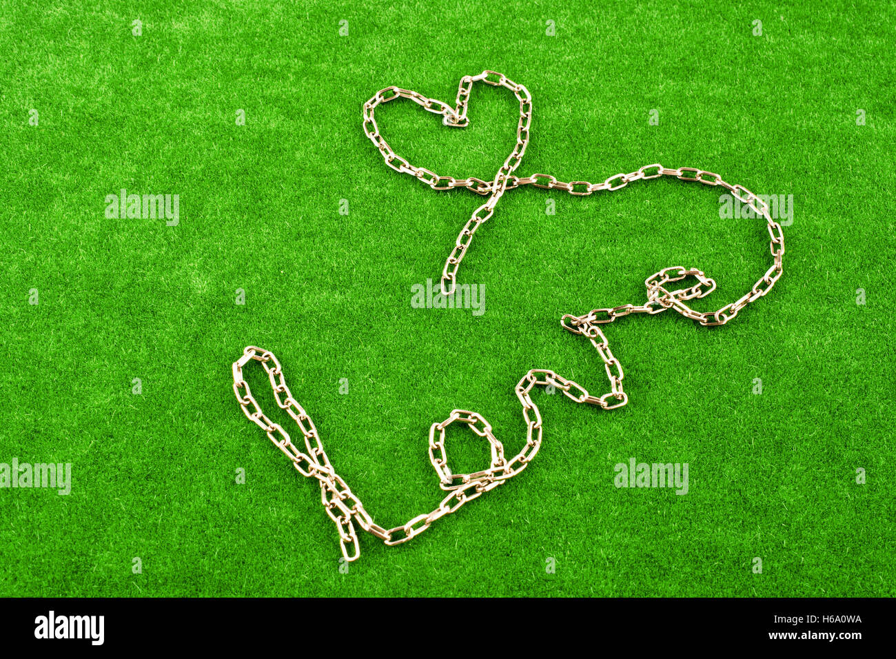 Forma di catena a forma di cuore e la parola amore sull'erba Foto Stock