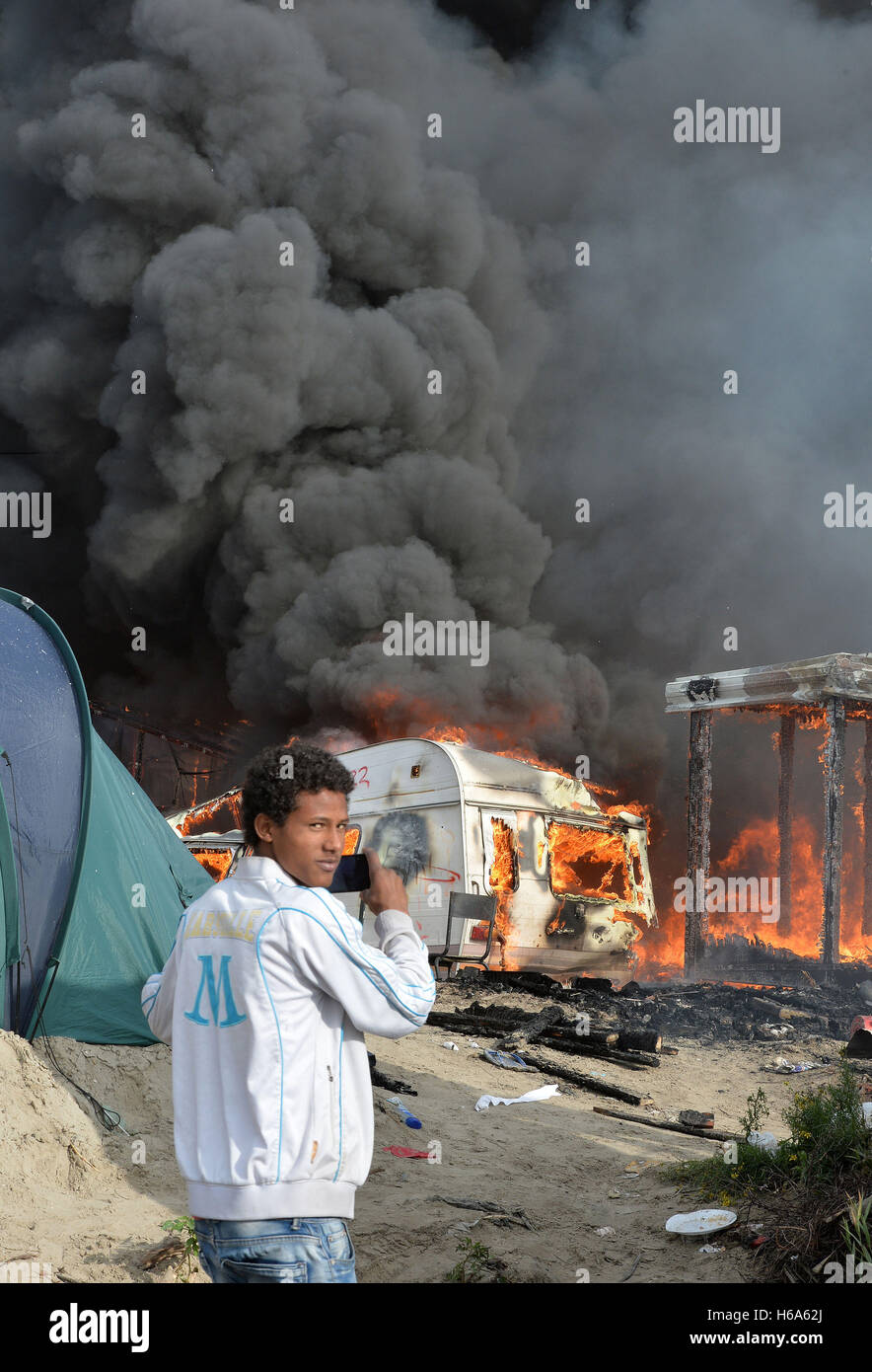 Il fumo sale oltre la giungla di Calais camp, come diversi grandi incendi scoppiati nel deserto vicino a campo migrante nel nord della Francia il terzo giorno dell'operazione per cancellare. Foto Stock