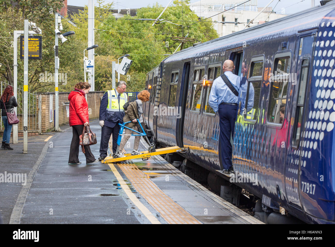 A Partick Stazione ferroviaria un passeggero utilizza la rampa disabili a bordo di un treno. Foto Stock