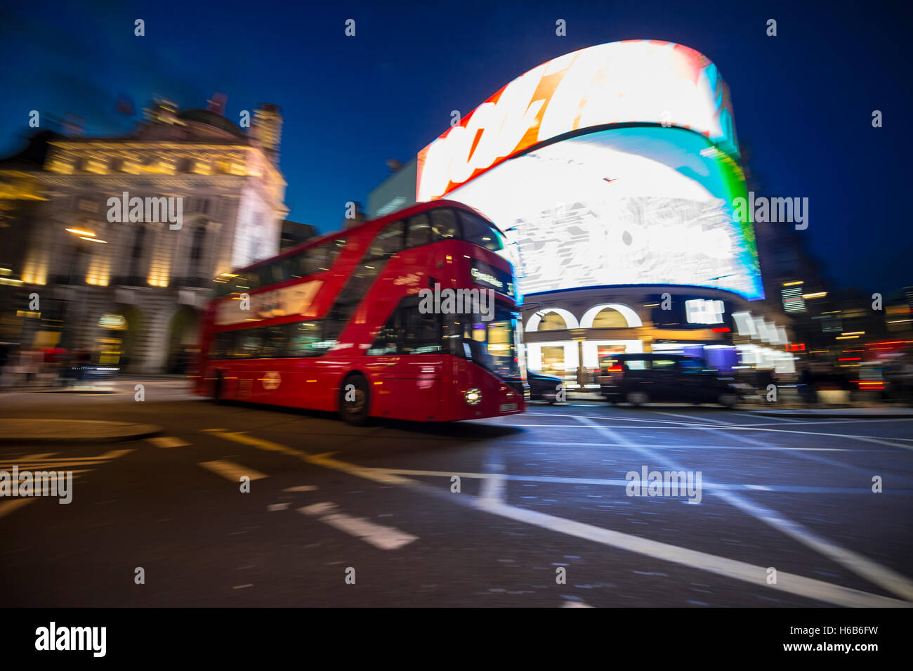Londra - Ottobre 1, 2016: modern double-decker bus passa attraverso le luci al neon di Piccadilly Circus in notturno di motion blur. Foto Stock