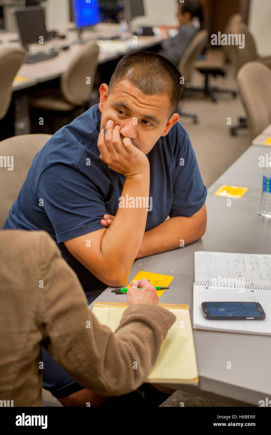 Una mezza età uomo ispanico si concentra su un tutor istruzioni nel centro di apprendimento di una Santa Ana CA Community College. Foto Stock