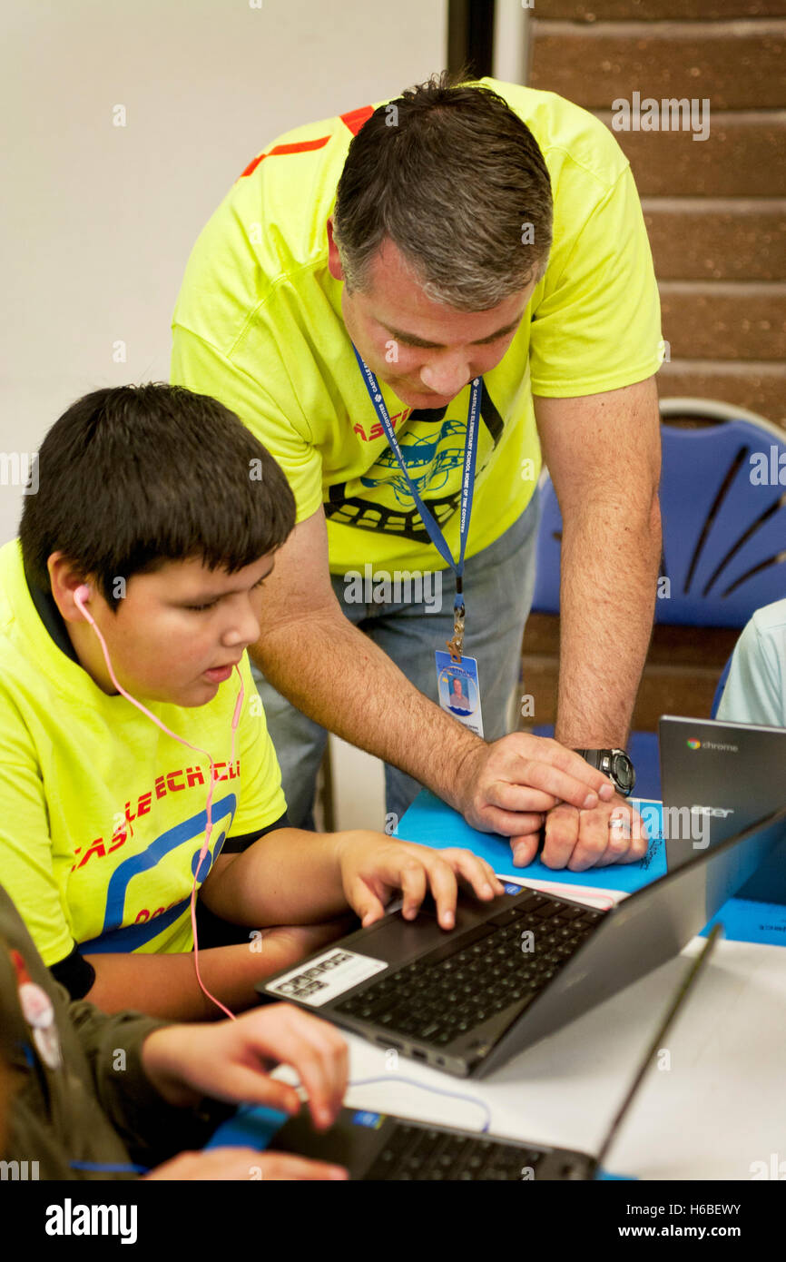 Un insegnante di scuola elementare aiuta i suoi studenti con una classe di animazione digitale il progetto in Mission Viejo, CA. Nota colorato progetto T Shirts. Foto Stock