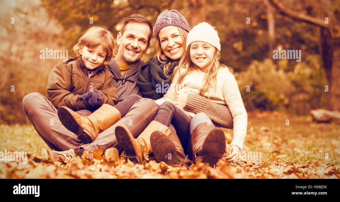 Sorridente giovane famiglia seduta in foglie Foto Stock