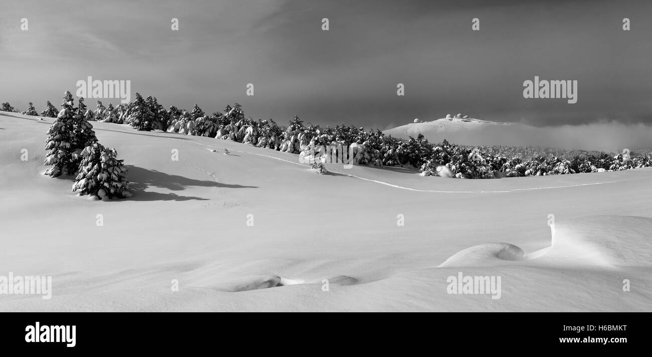 Vista panoramica del paesaggio invernale con pendii ricoperti di neve, abeti, foresta, edifici di forma sferica sulla collina; e bli Foto Stock