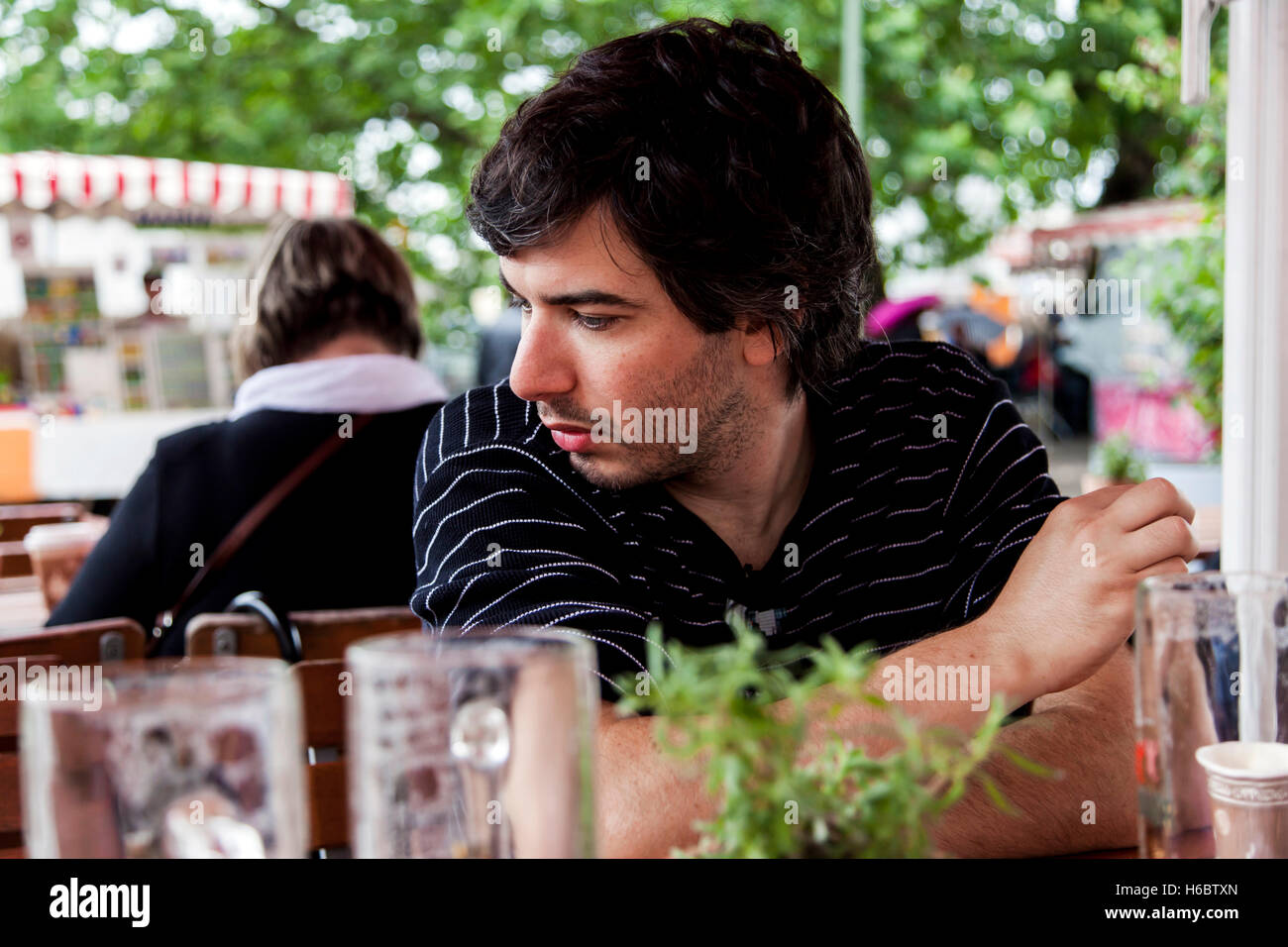 Ritratto di un uomo adulto nel suo 30s, seduti a un tavolo del bar. Foto Stock