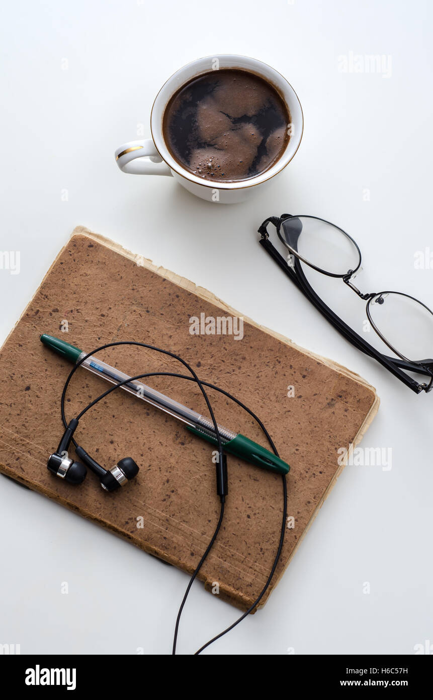 Caffè, notepad, auricolari e matita, sulla scrivania in ufficio. Foto Stock