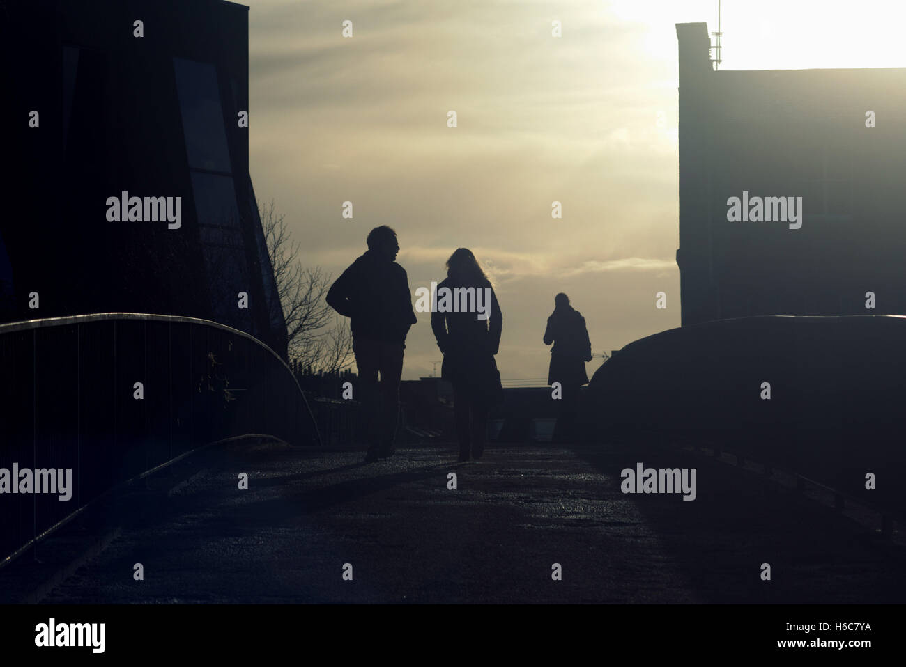 Silhouette di un giovane uomo e di una donna che parla su Glasgow street con road cont- jour retroilluminato in Glasgow, Scotland, Regno Unito. Foto Stock