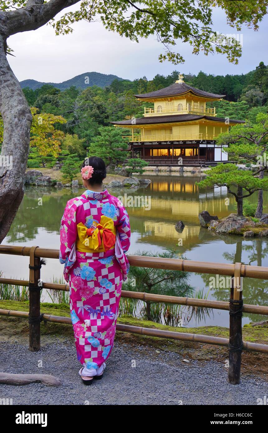 Una donna nel tradizionale kimono giapponese di fronte al tempio d'oro Padiglione (Kinkaku-ji) a Kyoto, in Giappone. Foto Stock