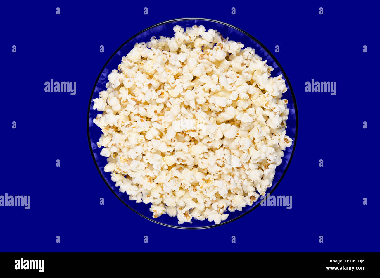 Popcorn schioccato in blu una ciotola di vetro su sfondo blu. A forma di farfalla di popcorn gonfiati dal kernel. Foto Stock