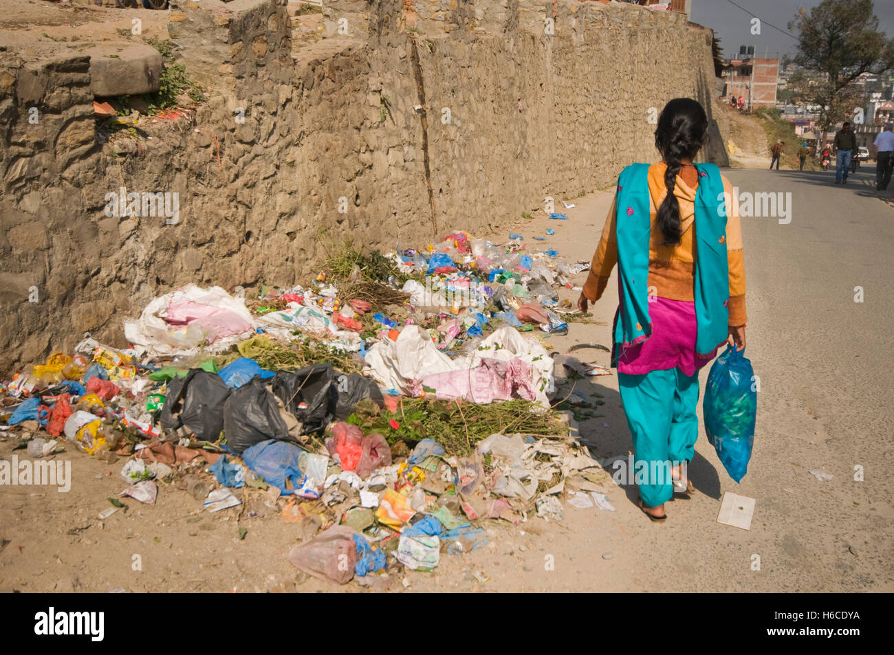 Il Nepal, Kathmandu, Pashupatinath, immondizia accatastati sulla strada, con donna locale a piedi da Foto Stock
