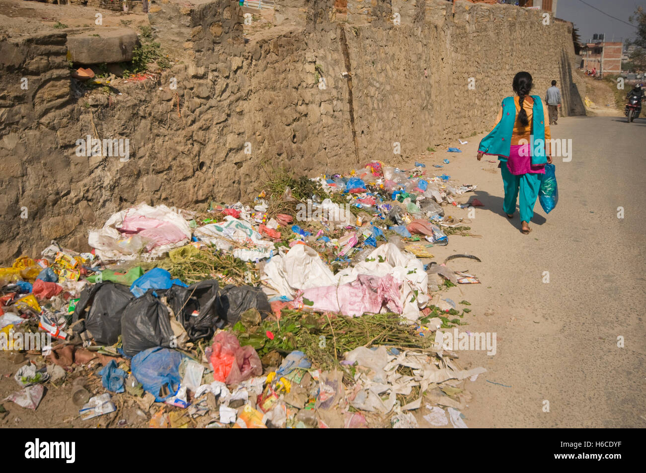 Il Nepal, Kathmandu, Pashupatinath, immondizia accatastati sulla strada, con donna locale a piedi da Foto Stock