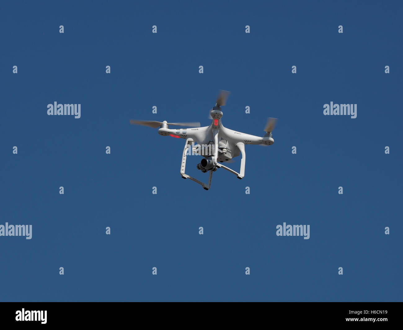 Sotto vista dal basso di un drone con fotocamera stabilizzatore flying overhead aeree contro un cielo blu Foto Stock Sotto vista dal basso di un drone con fotocamera stabilizzatore flying overhead aeree contro un cielo blu Foto Stock