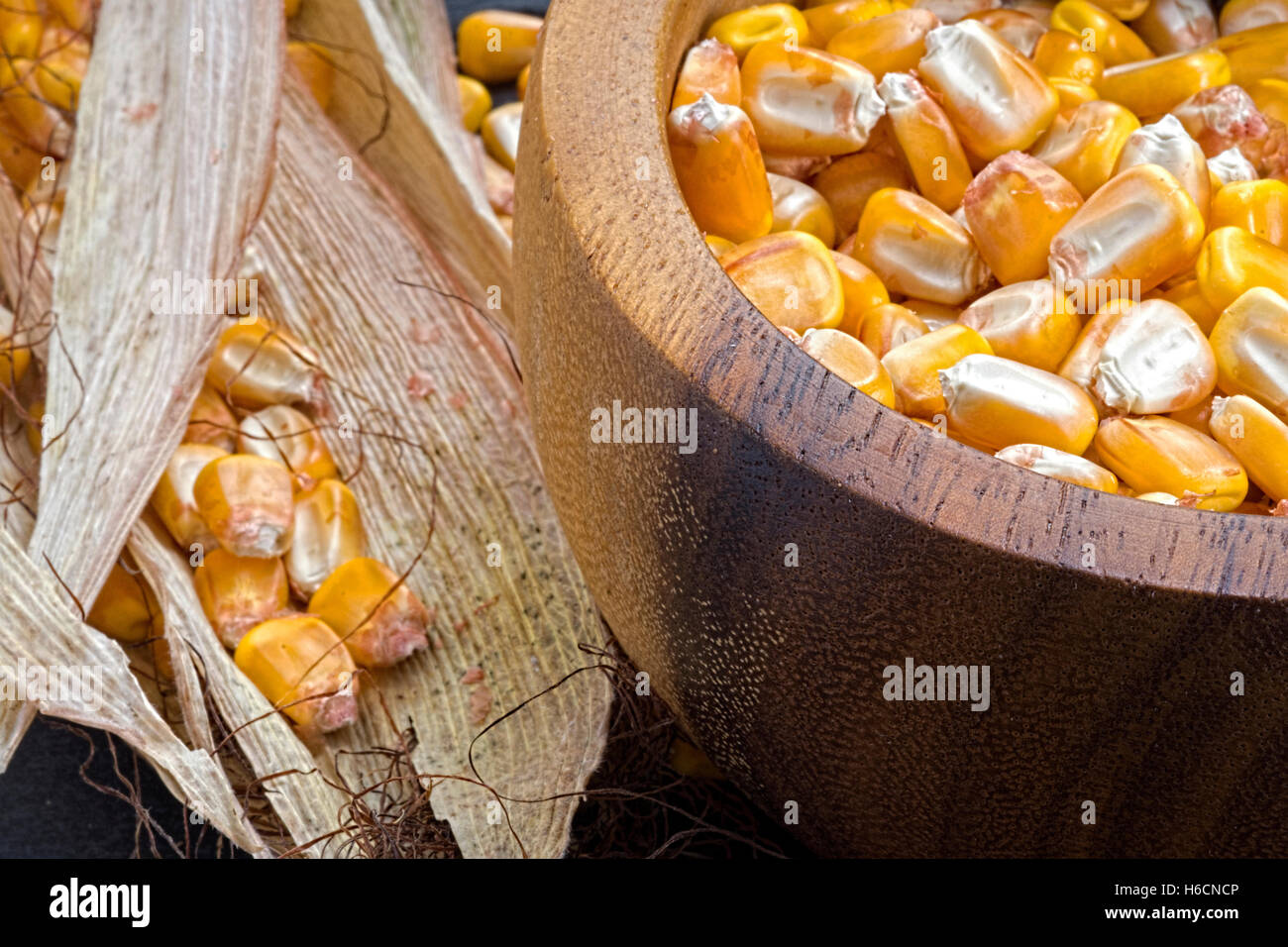 Chicchi di colore giallo mais maturi in ciotola di legno su sfondo rustico Foto Stock