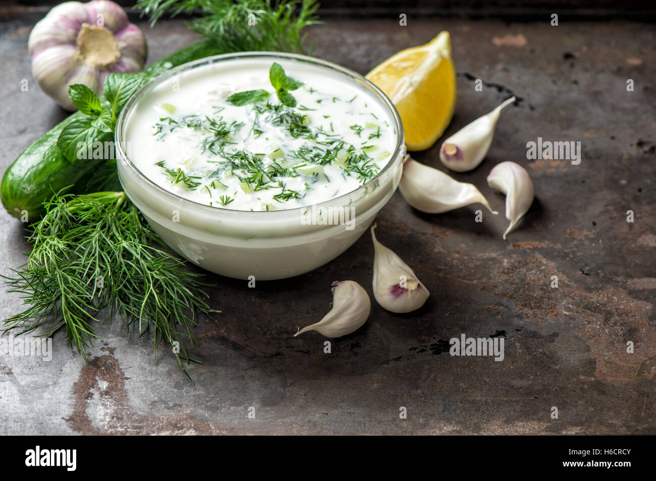 Salsa Tzatziki con ingredienti cetrioli, aglio, aneto, limone, menta. Cibo sano e sfondo Foto Stock