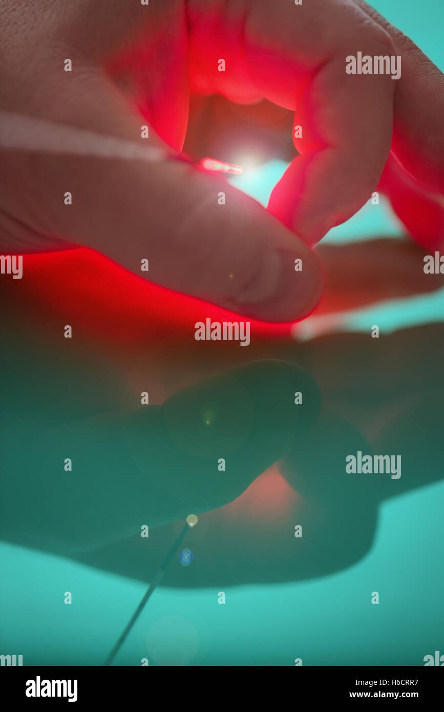 Fonte di luce intensa all'estremità della sonda per il trattamento mediante laser tra big e l'indice della mano sinistra Foto Stock