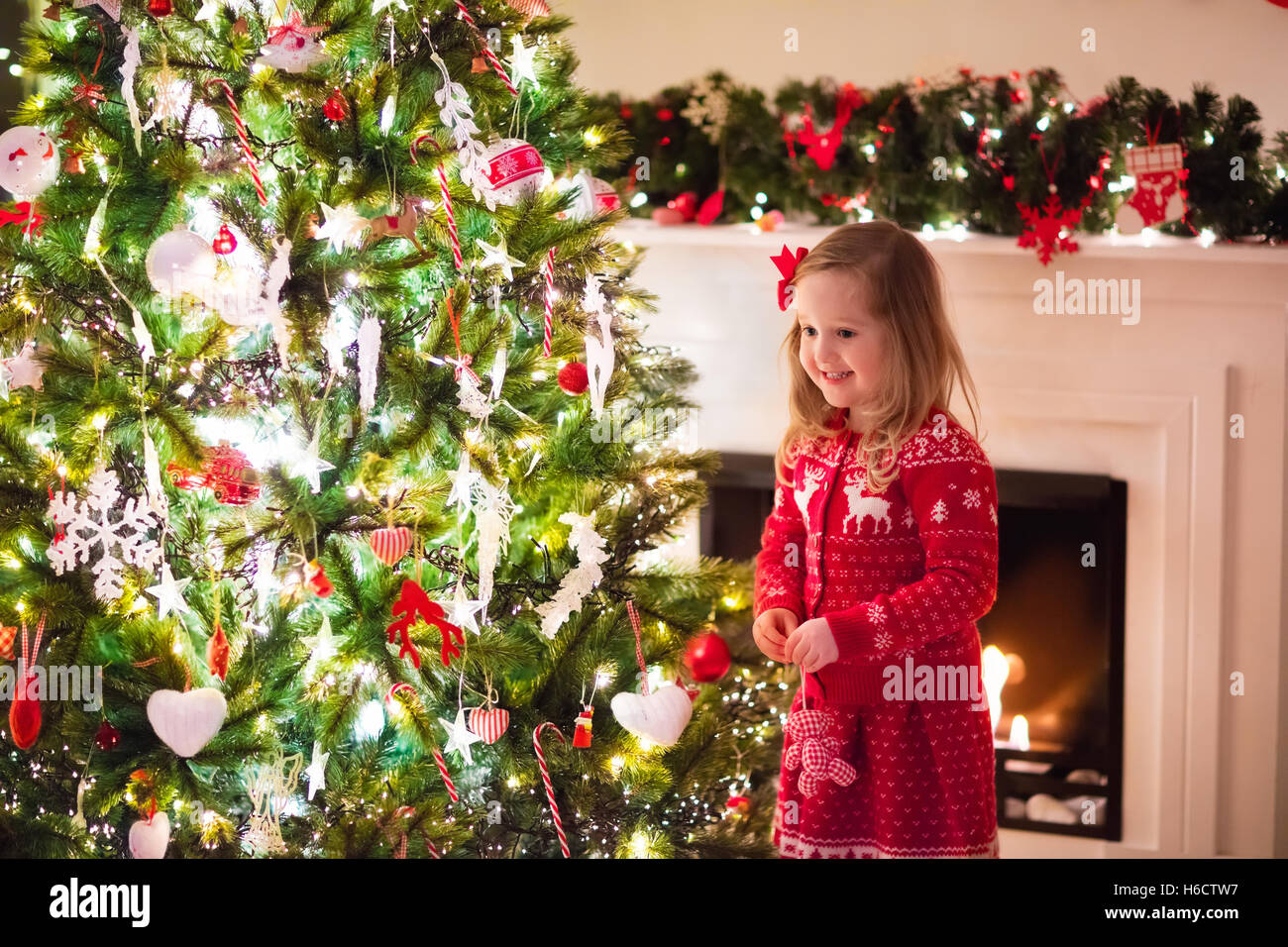 Bambina in maglia rossa Nordic renne maglione decorazioni su albero di  Natale con la luce, la pallina e canne di caramella Foto stock - Alamy