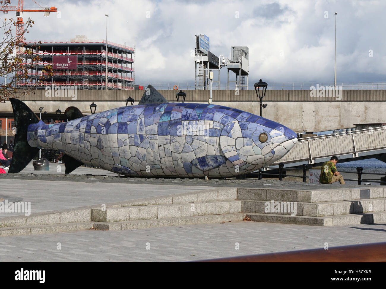 La grande scultura di pesce al Lagan Weir a Belfast. In background City Quays 2 è in costruzione presso il porto di Belfast. Foto Stock
